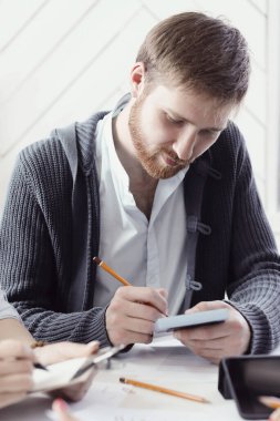 Genç işadamı ofiste yeni bir proje üzerinde çalışıyor.