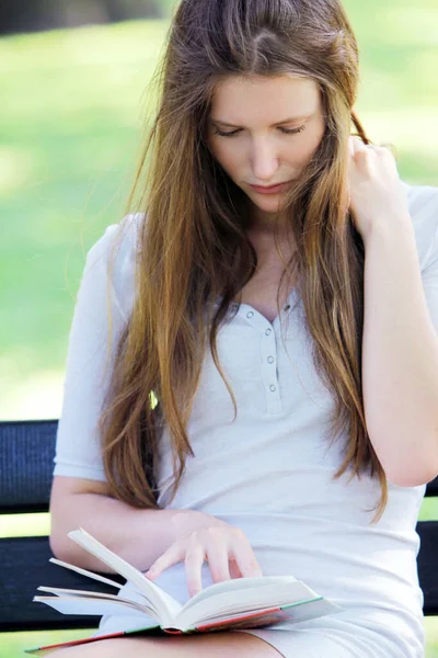 年轻漂亮的少女坐在长凳和读取书上 — 图库照片