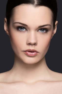 Gri arka planda sevimli, çekici bir kadın.