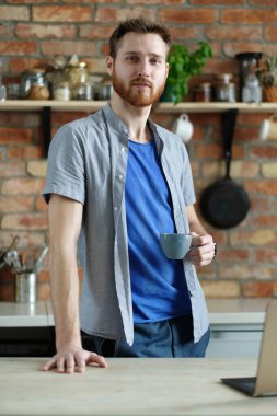 Sakallı yakışıklı genç adam mutfakta poz veriyor.