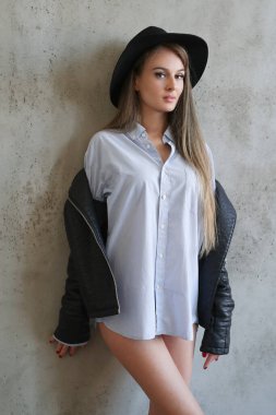 Gri duvarda siyah şapkalı güzel bir kadın.