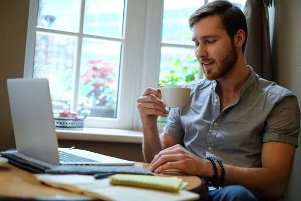 genç erkek serbest meslek sahibi Online kafede dizüstü kullanma ve içme kahve sohbet