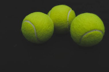 Siyah arka planda birkaç tenis topu var.