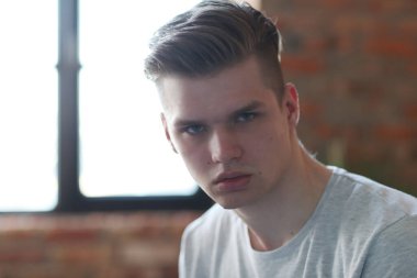 Duvarın arkasında poz veren yakışıklı genç adam.