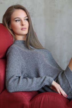 Güzel seksi kadın kırmızı koltukta poz veriyor.