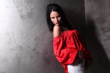 Moda. Kadın Kırmızı elbiseli bir beton duvar arka plan üzerinde poz