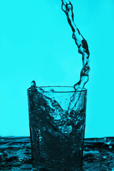 Liquid pouring into the glass over blue background