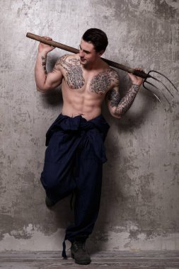 Elinde yaba tutan dövmeli bir adam.