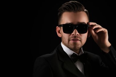 Siyah takım elbiseli çekici bir adam ve kelebek.