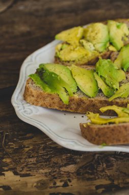 Tahta bir masada nefis avokado sandviçi.
