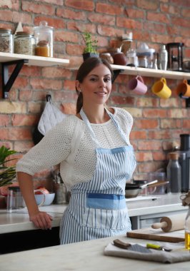 Genç ve güzel bir kadın mutfakta yemek pişiriyor. El yapımı yemek.