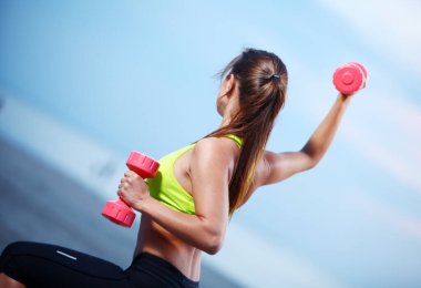 güzel bir kadın sahilde dumbbells ile yapıyor