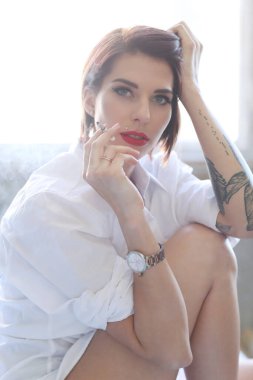Beautiful girl is posing on a bed with cigarette