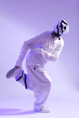 Beyaz kostümlü şık hip hop dansçısı stüdyoda dans ediyor.