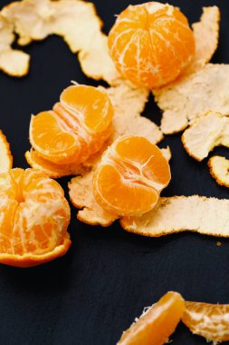 Siyah arkaplanda kabuklu mandalinalar