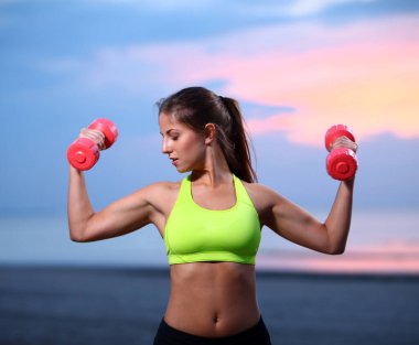 güzel bir kadın sahilde dumbbells ile yapıyor