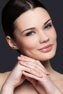 Gri arka planda sevimli, çekici bir kadın.