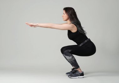 Beyaz arka planda egzersiz yapan genç bir kadın.