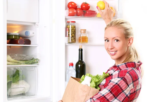 年轻和快乐的女人把食物放进冰箱里 — 图库照片