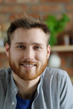 Sakallı yakışıklı genç adam mutfakta poz veriyor.