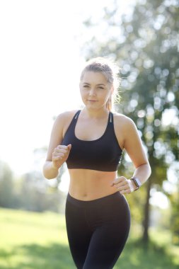 Parkta spor yapan genç bir kadın.