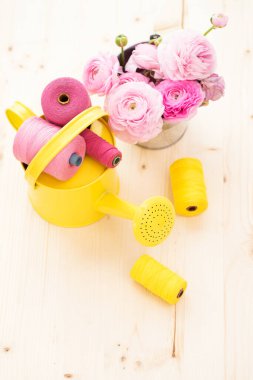 Terzilik. İplikler ve çiçekler masanın üstünde.