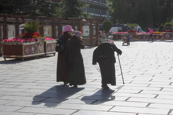 Eylül 'ün güneşli bir gününde, Lhasa, Tibet' te Barkhor Meydanı 'nda üç yaşlı kadın günlük kıyafetleriyle yürüyor.