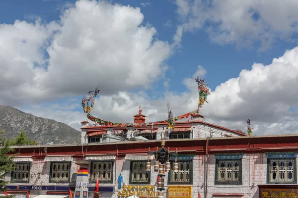 Lhasa 'da beyaz tuğladan yapılmış bir bina. Pencere çitleri oyulmuş ve üzerinde öküz boynuzu şeklinde bayraklar, Lhasa, Tibet manzarası var.