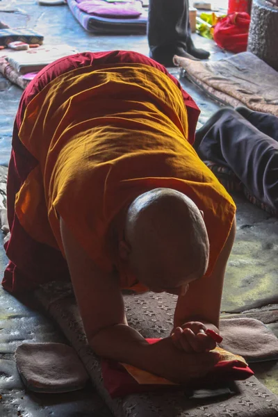 Tibet Barkhor Meydanı 'ndaki Lhasa' da Jokhang tapınağının önünde geleneksel kırmızı ve sarı giysiler içinde dua eden cesur bir keşiş.