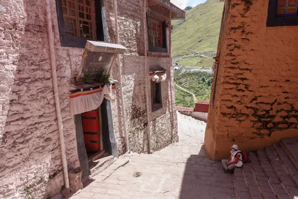 Drepung kolostor mindössze 8 km-re Lhasa, Tibet, Ázsia, fehér és piros épületek, nő ül és pihen — Stock Fotó