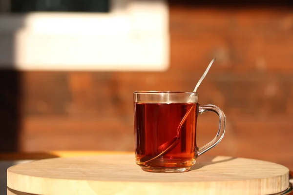 Eine Tasse Tee mit Löffel auf dem Holztisch im Garten — Stockfoto