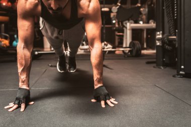 Spor salonundaki sportif bir adam yoga egzersizleri yapıyor, kalas pozisyonunda duruyor, şınav çekiyor ya da egzersiz yapıyor, tüm uzunluğu kapsıyor..
