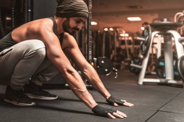 Spor salonunda sakallı bir sporcu yoga egzersizi yapıyor. Adam silah pozisyonuna hazırlanıyor. Yoga zihinsel faydaları.