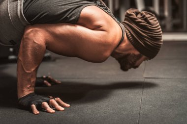 Spor salonunda sakallı bir sporcu yoga egzersizi yapıyor. Kollar pozisyona. Yoga zihinsel faydaları. Bakasana veya karga pozu.