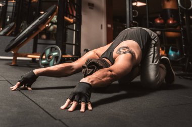 Spor salonunda sporcu bir adam yoga egzersizi yapıyor. Sırt germe egzersizi. Yoga pozisyonu Sasangasana. Yoga zihinsel faydaları.