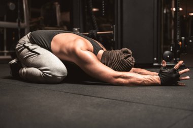 Spor salonunda sporcu bir adam yoga egzersizi yapıyor. Sırt germe egzersizi. Yoga pozisyonu Sasangasana. Yoga zihinsel faydaları.