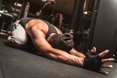Spor salonunda sporcu bir adam yoga egzersizi yapıyor. Sırt germe egzersizi. Yoga pozisyonu Sasangasana. Yoga zihinsel faydaları.