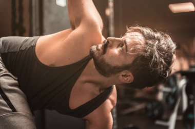 Spor salonunda sakallı bir sporcu Yoga ve Dövüş Sanatları egzersizi yapıyor. Dönen Üçgen Poz. Parivrtta Trikonasana Konumu. Yoga zihinsel faydaları.