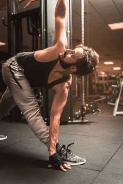 Spor salonunda sakallı bir sporcu Yoga ve Dövüş Sanatları egzersizi yapıyor. Dönen Üçgen Poz. Parivrtta Trikonasana Konumu. Yoga zihinsel faydaları.
