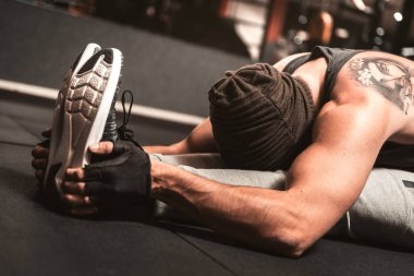 Spor salonunda sporcu bir adam yoga egzersizi yapıyor. Paschimottanasana konumu: otururken öne eğilme. Yoga zihinsel faydaları.