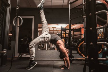 Spor salonunda sporcu bir adam yoga egzersizi yapıyor. Sirsasana ya da Kapalasana, baştaki pozisyon. Yoga zihinsel faydaları.