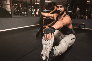 Adam spor salonunda yoga yapıyor, paschimottanasana egzersizinde oturuyor. Öne eğik poz verin. Yoga zihinsel faydaları.