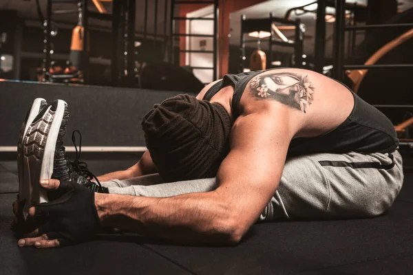 A sporty man in the gym is doing Yoga exercises. Paschimottanasana position: forward bending when seated. Yoga mental benefits.