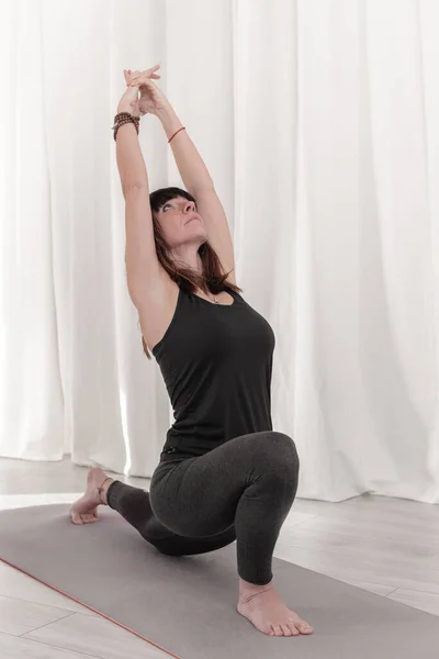 Woman does exercises of yoga. Warrior or Virabhadrasana pose. Surya Namaskar sequence. How to Keep Your Arms in the Air for a Kriya or Meditation.