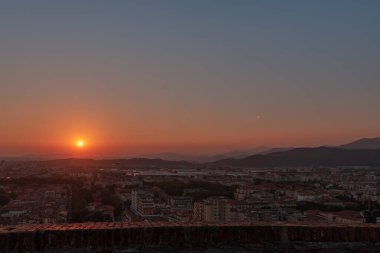Brescia şehrinin ve Alp dağlarının binalarının bulunduğu hava panoramik günbatımı manzarası, mavi bulutlu arka plan, Lombardy, Kuzey İtalya. Brescia Kalesi.
