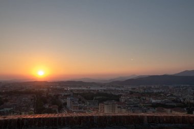 Brescia şehrinin ve Alp dağlarının binalarının bulunduğu hava panoramik günbatımı manzarası, mavi bulutlu arka plan, Lombardy, Kuzey İtalya. Brescia Kalesi.