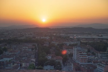Brescia şehrinin ve Alp dağlarının binalarının bulunduğu hava panoramik günbatımı manzarası, mavi bulutlu arka plan, Lombardy, Kuzey İtalya. Brescia Kalesi.