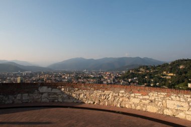 Brescia şehrinin ve Alp dağlarının binalarının bulunduğu hava panoramik günbatımı manzarası, mavi bulutlu arka plan, Lombardy, Kuzey İtalya. Brescia Kalesi.