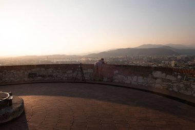 Brescia şehrinin ve Alp dağlarının binalarının bulunduğu hava panoramik günbatımı manzarası, mavi bulutlu arka plan, Lombardy, Kuzey İtalya. Brescia Kalesi.