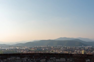 Brescia şehrinin ve Alp dağlarının binalarının bulunduğu hava panoramik günbatımı manzarası, mavi bulutlu arka plan, Lombardy, Kuzey İtalya. Brescia Kalesi.